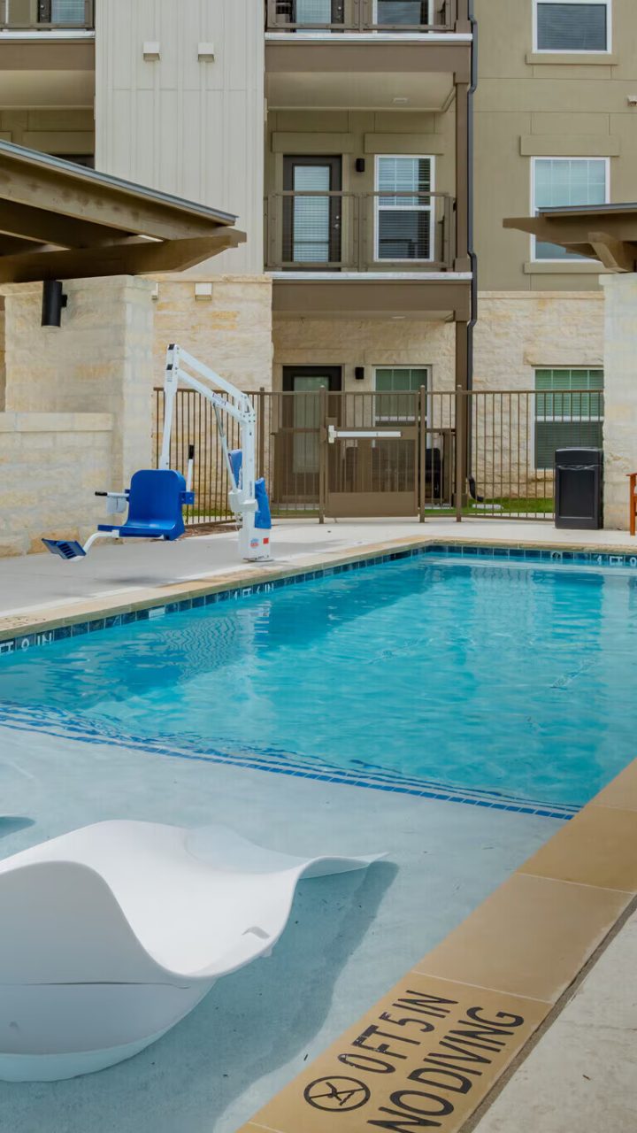 a pool with lounge chairs and a patio area at The Barons Park
